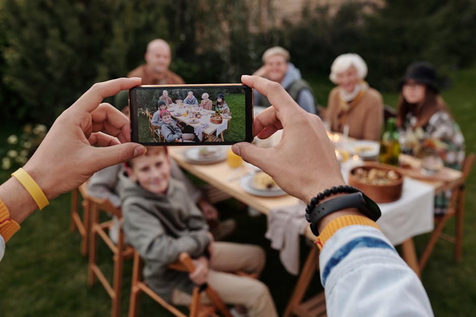 Die Vorteile der Digitalisierung von Familienfotos und Filmen: Unrecognizable person taking photo of family dinner on smartphone Unrecognizable Person Taking Photo Of Family Dinner On Smartphone